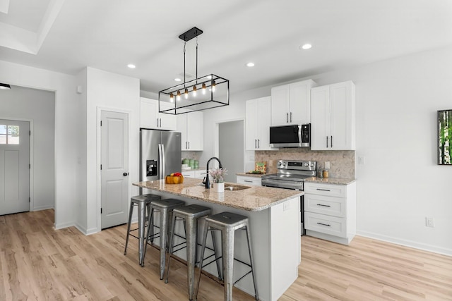 kitchen featuring tasteful backsplash, a breakfast bar area, appliances with stainless steel finishes, a kitchen island with sink, and a sink