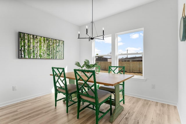 dining area featuring a notable chandelier, baseboards, and wood finished floors