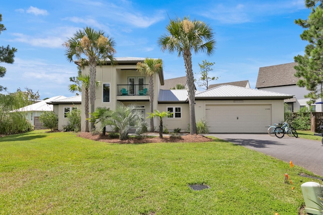 view of front facade featuring an attached garage, metal roof, a balcony, driveway, and a front lawn