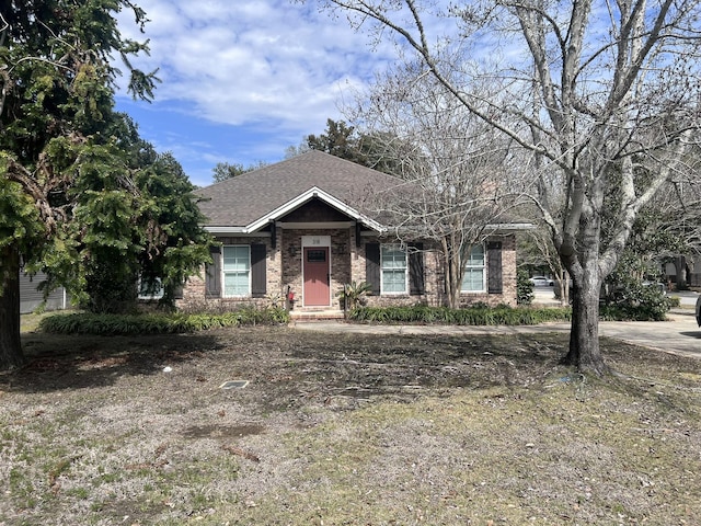 ranch-style home featuring brick siding and roof with shingles