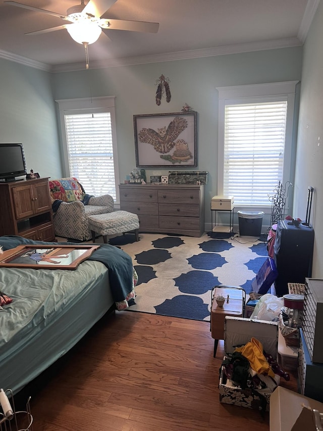 bedroom with multiple windows, a ceiling fan, wood finished floors, and crown molding