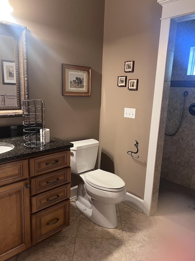 full bath with vanity, toilet, baseboards, and tiled shower