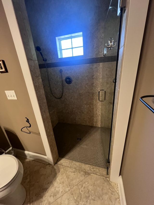 full bath featuring baseboards, toilet, a stall shower, and tile patterned flooring