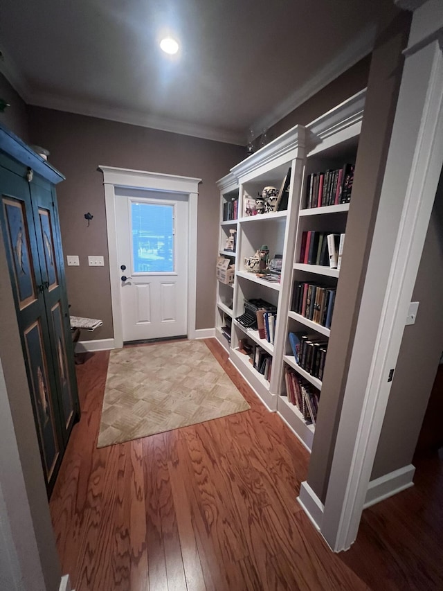 interior space featuring wood finished floors, baseboards, and ornamental molding