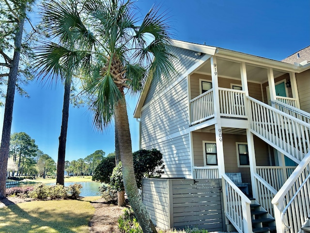 view of home's exterior featuring a porch, a water view, and stairway