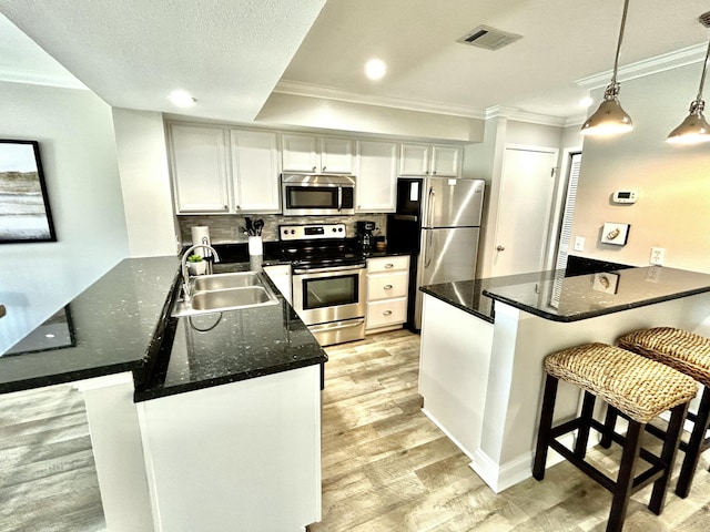 kitchen with stainless steel appliances, visible vents, light wood-style flooring, and a peninsula