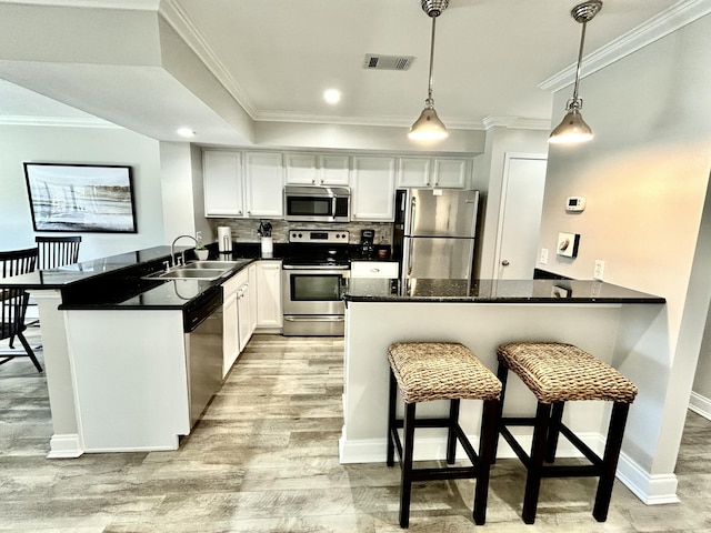 kitchen featuring visible vents, decorative backsplash, appliances with stainless steel finishes, a peninsula, and a sink