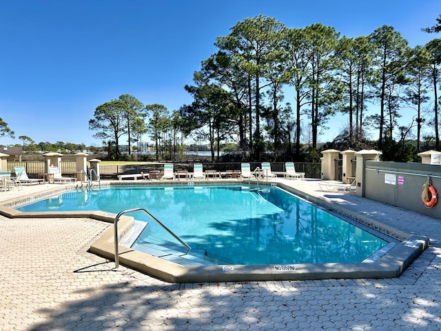 community pool with a patio area and fence