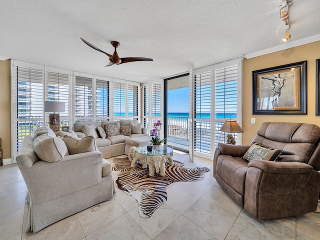 tiled living area with ceiling fan, a textured ceiling, a water view, expansive windows, and track lighting