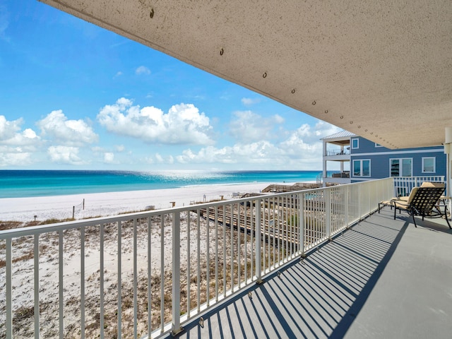 balcony featuring a view of the beach and a water view