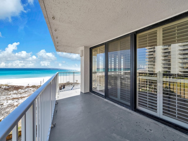 balcony featuring a view of the beach and a water view