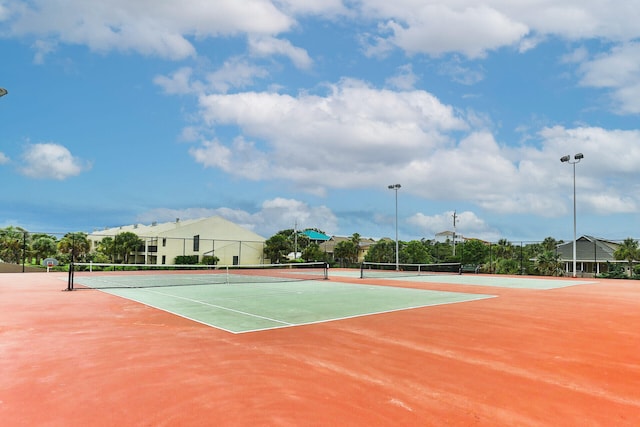 view of tennis court featuring community basketball court and fence