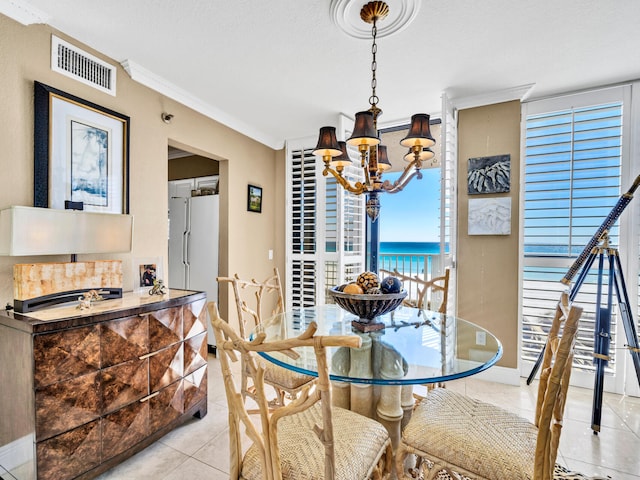 dining space with light tile patterned floors, baseboards, visible vents, ornamental molding, and a chandelier