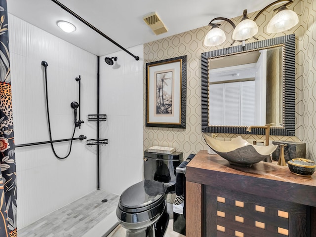 bathroom featuring wallpapered walls, visible vents, a tile shower, and vanity