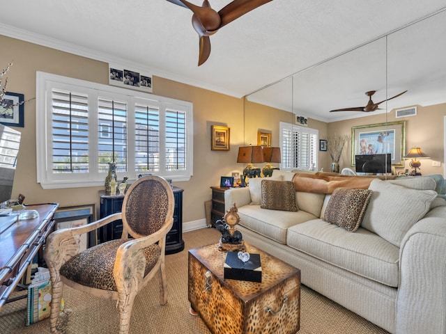 living area with ornamental molding, visible vents, ceiling fan, and baseboards