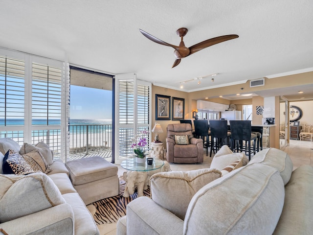 living room featuring a textured ceiling, ornamental molding, a wall of windows, and visible vents