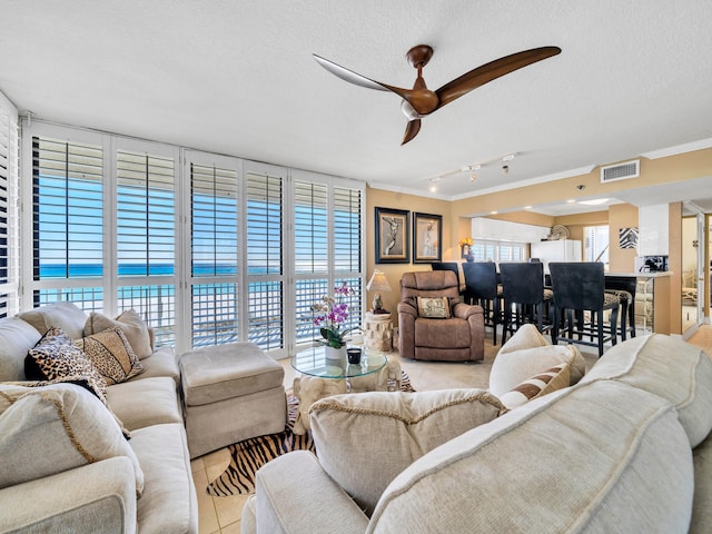 living area featuring visible vents, ornamental molding, light tile patterned flooring, a textured ceiling, and plenty of natural light