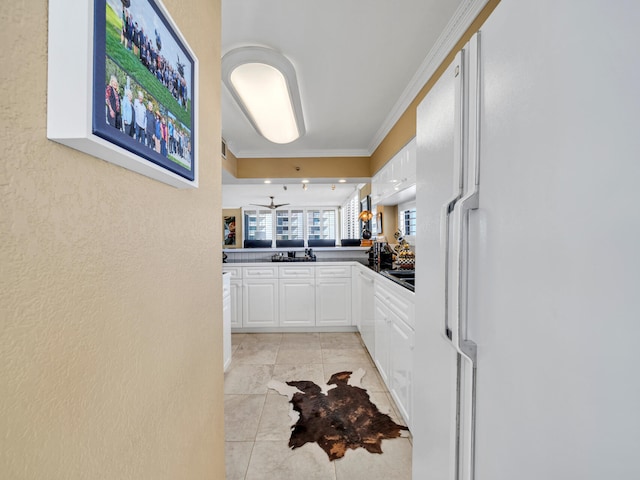 kitchen featuring freestanding refrigerator, white cabinets, crown molding, and dark countertops