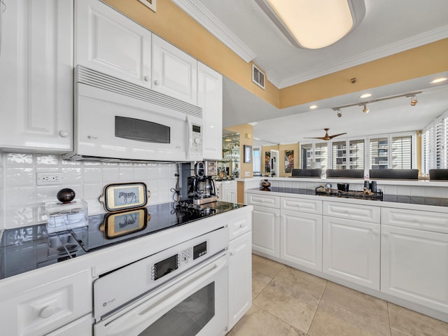 kitchen featuring white appliances, visible vents, white cabinets, backsplash, and crown molding