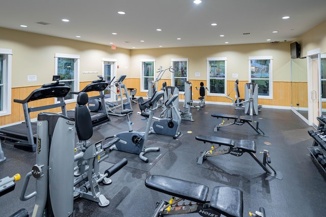 exercise room featuring a wainscoted wall, wooden walls, and recessed lighting