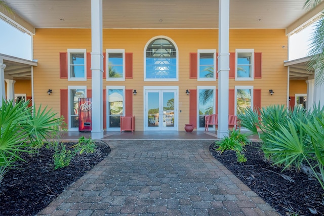 view of exterior entry with covered porch and french doors