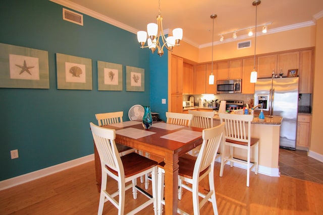 dining space with ornamental molding, visible vents, and light wood-style flooring