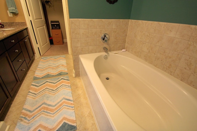 bathroom with tile patterned flooring, a garden tub, vanity, and a spacious closet