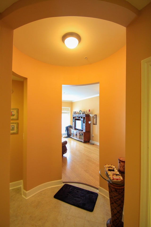 hall featuring arched walkways, tile patterned flooring, and baseboards