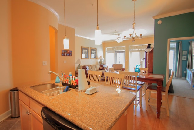 kitchen featuring pendant lighting, ornamental molding, open floor plan, a sink, and dishwasher