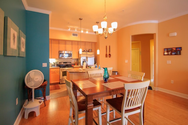 dining area featuring a chandelier, light wood-type flooring, visible vents, and crown molding