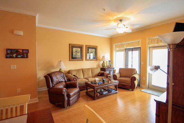 living room with baseboards, ceiling fan, light wood-style flooring, and crown molding