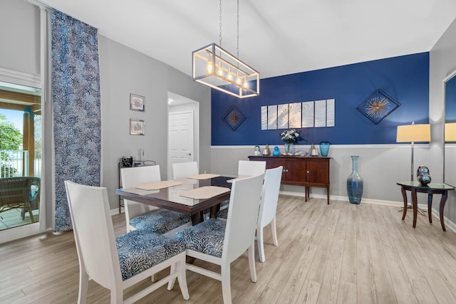 dining space featuring light wood-style floors, baseboards, and an inviting chandelier