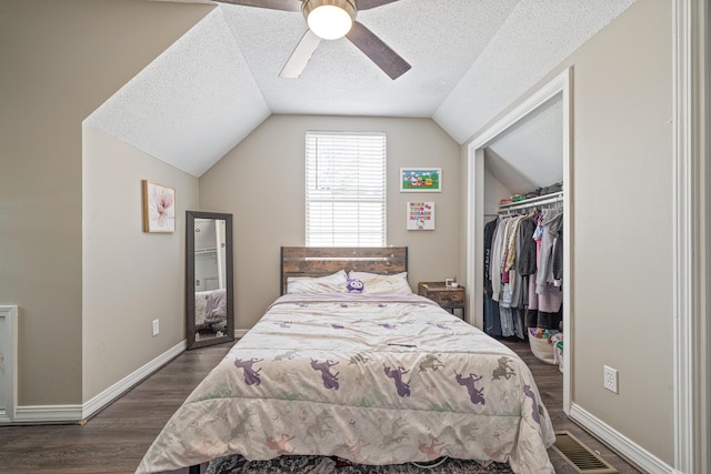 bedroom with dark wood finished floors, visible vents, vaulted ceiling, a textured ceiling, and baseboards