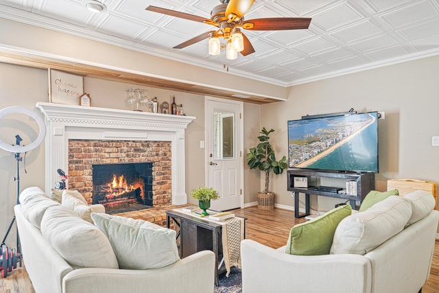 living room featuring baseboards, an ornate ceiling, ceiling fan, wood finished floors, and a fireplace