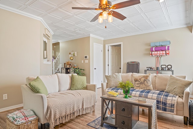 living area with baseboards, a ceiling fan, an ornate ceiling, stairs, and light wood-style floors