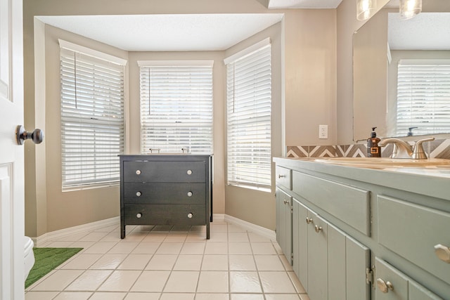 bathroom with tile patterned flooring, vanity, baseboards, and a textured ceiling