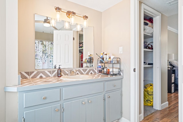 full bathroom featuring a shower with shower curtain, wood finished floors, a spacious closet, a textured ceiling, and vanity