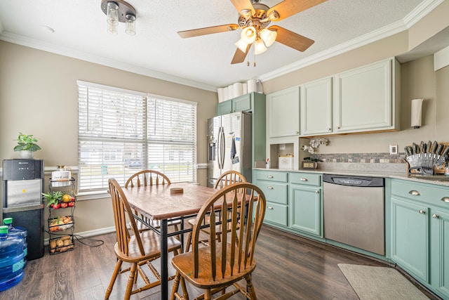 kitchen with dark wood finished floors, stainless steel appliances, green cabinets, ornamental molding, and a textured ceiling