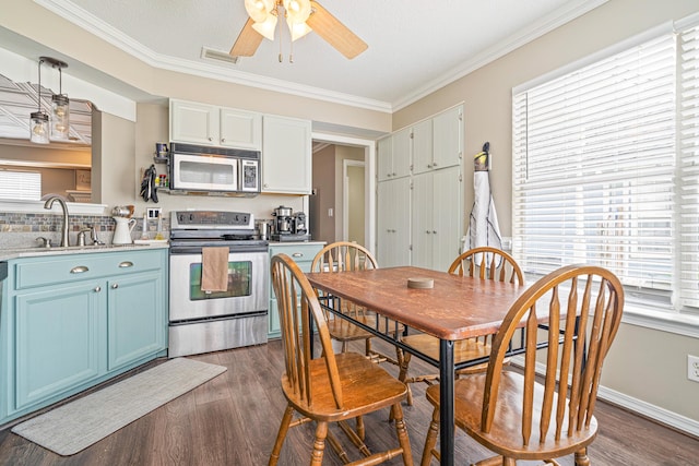 kitchen featuring stainless steel appliances, crown molding, blue cabinetry, and dark wood-style floors