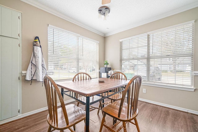 dining area with a textured ceiling, baseboards, wood finished floors, and crown molding