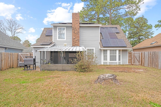 rear view of house featuring solar panels, a lawn, and a sunroom