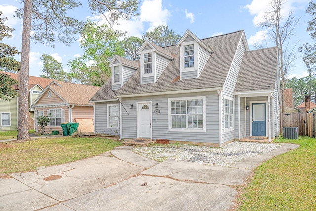 cape cod home featuring a shingled roof, fence, a front lawn, and cooling unit