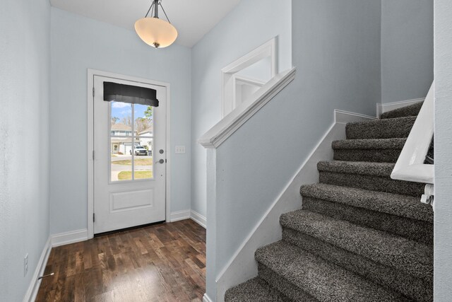 foyer entrance featuring stairs, baseboards, and wood finished floors