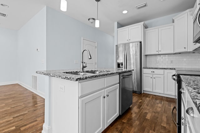 kitchen with appliances with stainless steel finishes, visible vents, a sink, and dark stone countertops