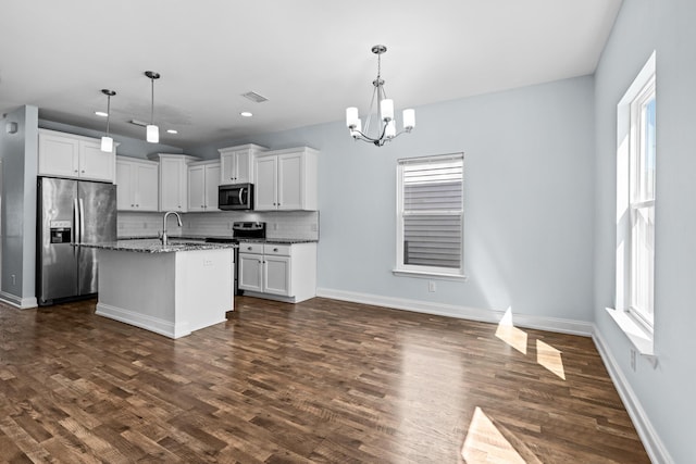 kitchen with stainless steel appliances, backsplash, an inviting chandelier, dark wood-type flooring, and a sink