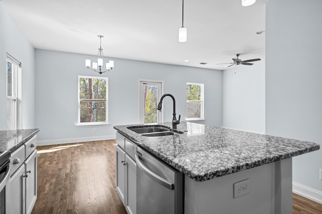 kitchen with a center island with sink, dark wood finished floors, dishwasher, dark stone countertops, and a sink