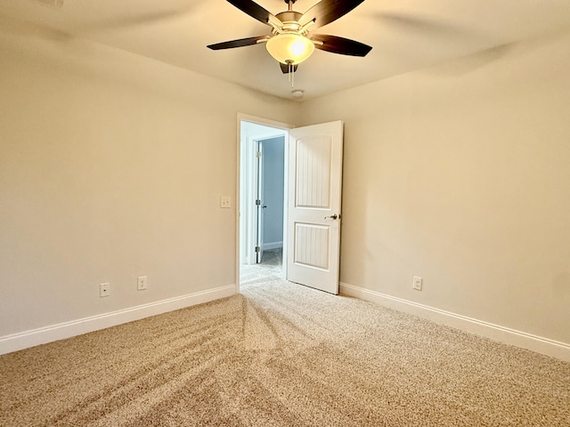 carpeted empty room with a ceiling fan and baseboards