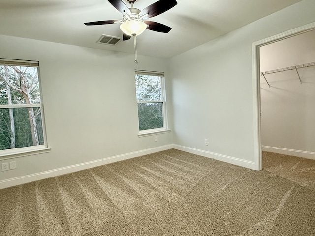 unfurnished bedroom with carpet floors, a walk in closet, a closet, visible vents, and baseboards