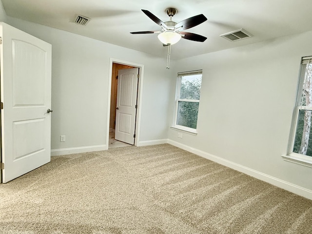 empty room featuring light colored carpet, visible vents, and baseboards