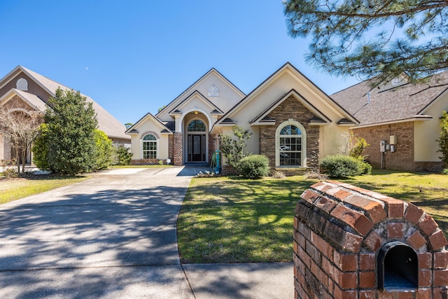 view of front of home featuring driveway, brick siding, and stucco siding